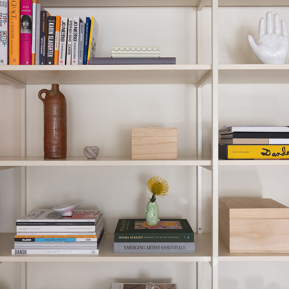 bokhylla i off white med böcker och lådor 